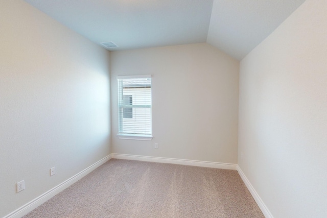 carpeted spare room with lofted ceiling