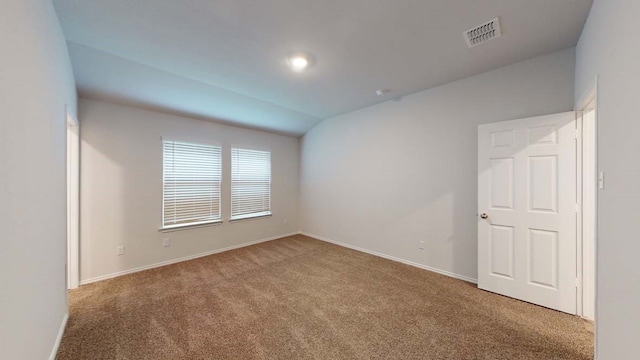 carpeted empty room featuring lofted ceiling