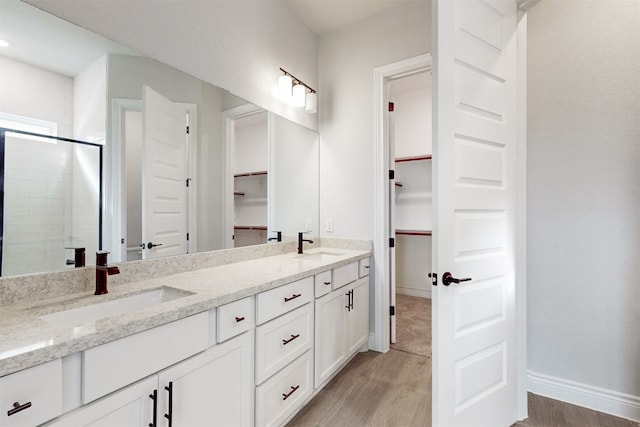 bathroom with hardwood / wood-style floors, vanity, and a shower with shower door