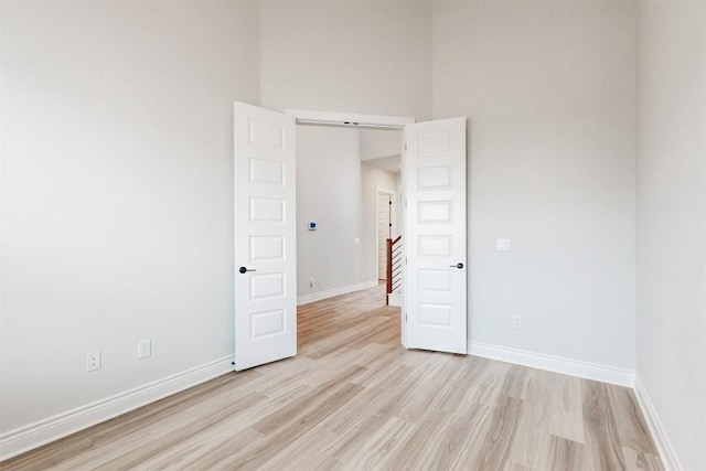 spare room with a high ceiling and light wood-type flooring