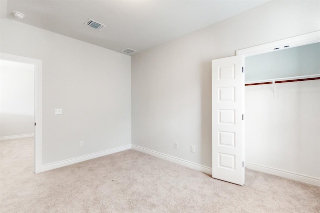 unfurnished bedroom featuring a closet and light colored carpet