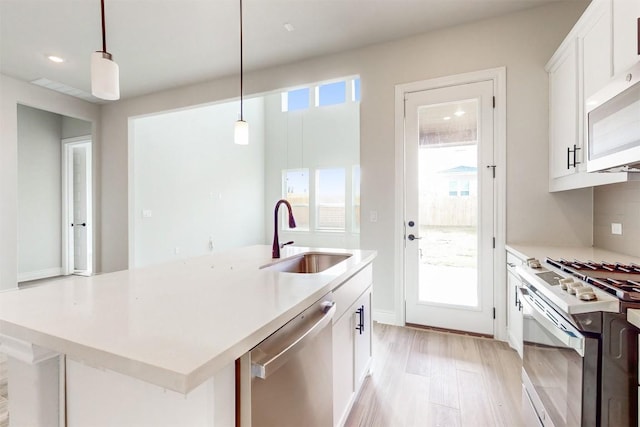 kitchen with sink, an island with sink, decorative light fixtures, white appliances, and white cabinets