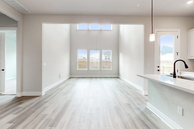 unfurnished living room with a healthy amount of sunlight, light hardwood / wood-style floors, and sink