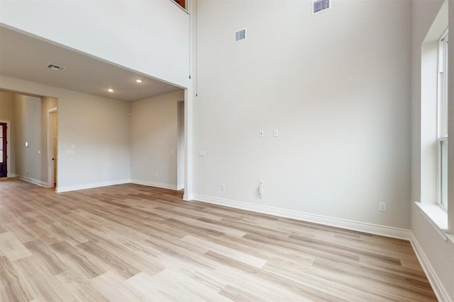 empty room featuring light hardwood / wood-style floors and a high ceiling