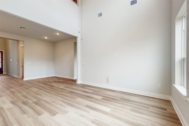 empty room featuring light hardwood / wood-style floors and a high ceiling