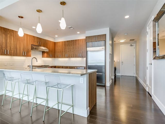 kitchen with stainless steel built in refrigerator, dark hardwood / wood-style flooring, decorative light fixtures, and extractor fan