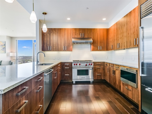 kitchen featuring hanging light fixtures, sink, premium appliances, range hood, and dark hardwood / wood-style flooring