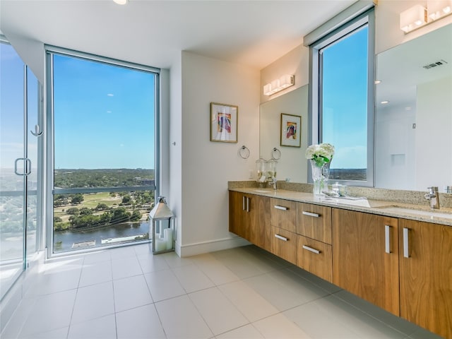 bathroom featuring a water view, a shower with door, vanity, and tile patterned floors