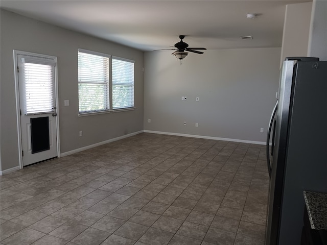 kitchen with stone counters, ceiling fan, stainless steel refrigerator, and tile patterned flooring