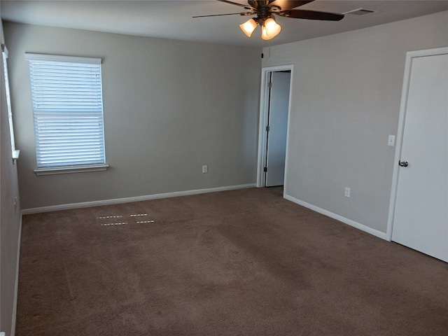 unfurnished room with ceiling fan and dark colored carpet