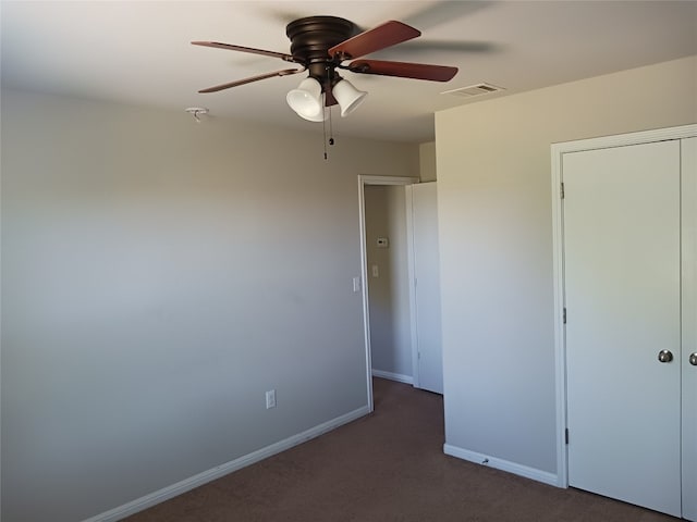 unfurnished bedroom featuring dark carpet, a closet, and ceiling fan