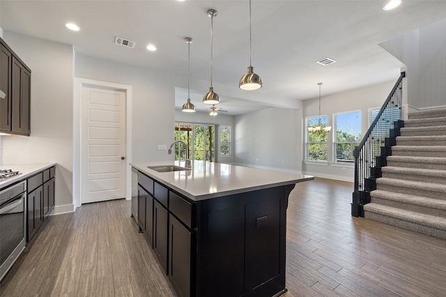 kitchen with hardwood / wood-style floors, a kitchen island with sink, sink, and ceiling fan