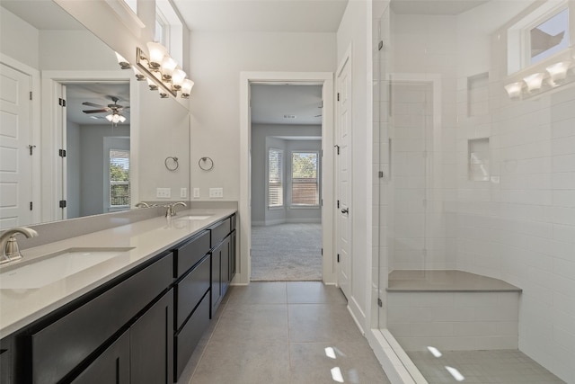 bathroom with ceiling fan, tile patterned flooring, tiled shower, and vanity