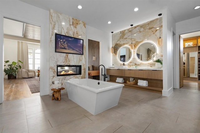 bathroom with a fireplace, hardwood / wood-style floors, vanity, and a washtub