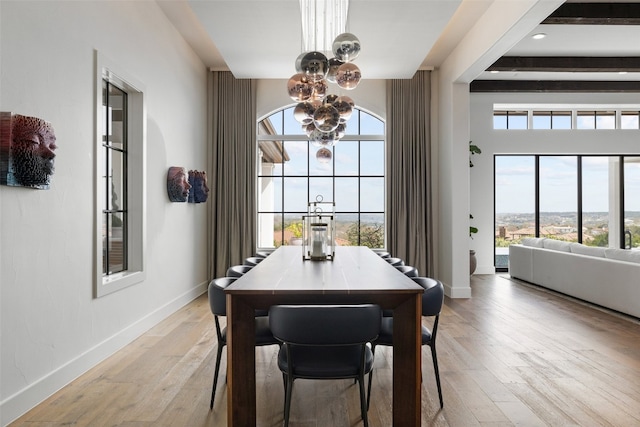 dining space featuring beamed ceiling, light wood-type flooring, and a notable chandelier