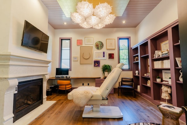 living area with hardwood / wood-style floors, built in desk, wood ceiling, and an inviting chandelier