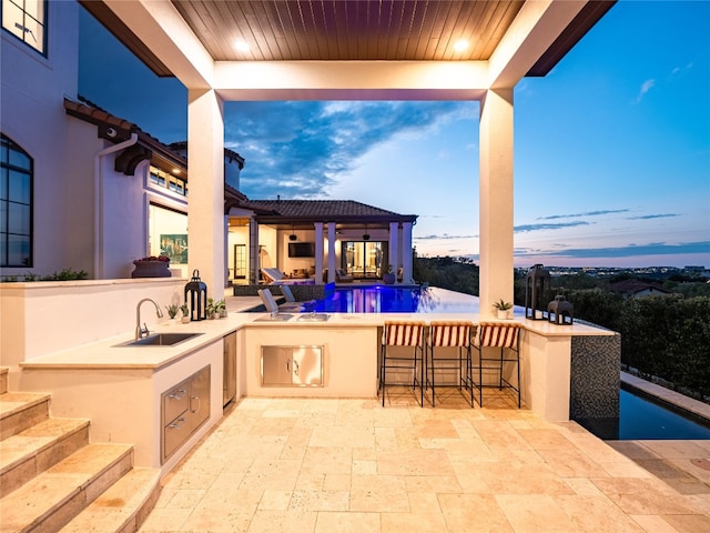 view of patio / terrace with area for grilling, pool water feature, and an outdoor wet bar