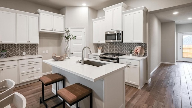 kitchen with white cabinetry, appliances with stainless steel finishes, a kitchen breakfast bar, and a kitchen island with sink