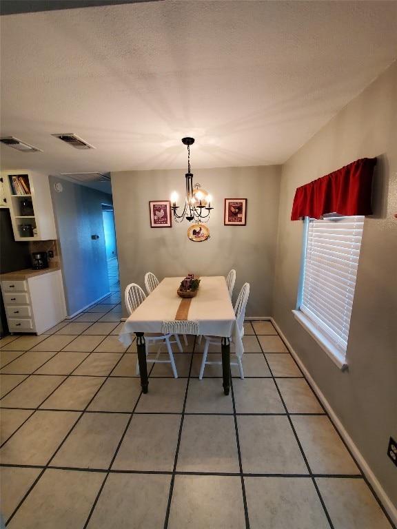 tiled dining space featuring a textured ceiling and a notable chandelier