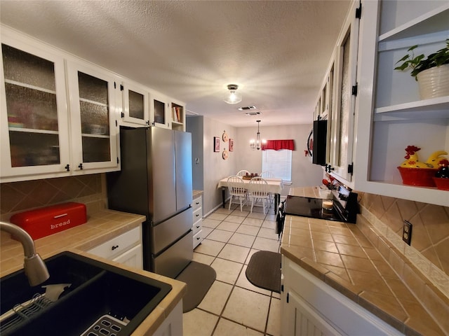 kitchen featuring white cabinets, tile countertops, sink, and tasteful backsplash