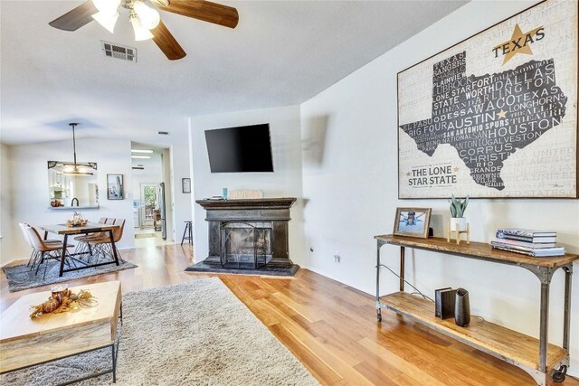 4316 Campo Verde Dr, Austin, TX 78749 - living area featuring wood finished floors, a ceiling fan, and a fireplace with raised hearth