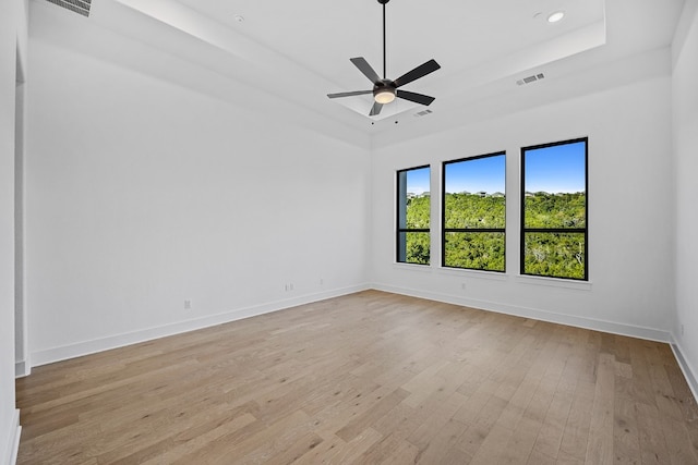 unfurnished room with ceiling fan, light hardwood / wood-style flooring, and a raised ceiling