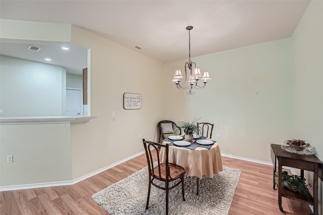 dining space with light hardwood / wood-style floors and an inviting chandelier