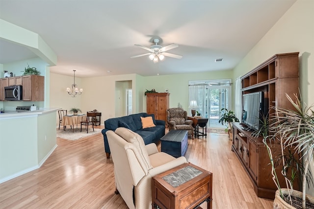 living room featuring light hardwood / wood-style flooring and ceiling fan with notable chandelier