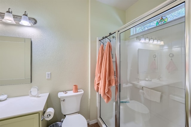 bathroom with vanity, a shower with shower door, and toilet