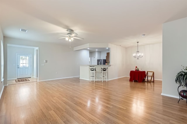 unfurnished living room featuring ceiling fan with notable chandelier and light wood-type flooring