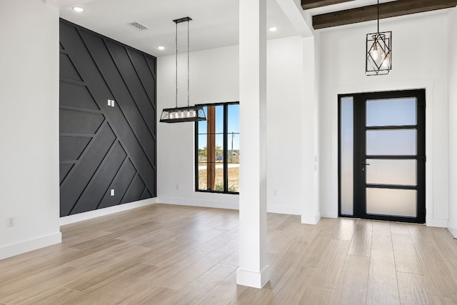 foyer featuring light hardwood / wood-style flooring, a high ceiling, beamed ceiling, and an inviting chandelier