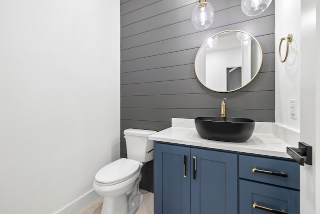 bathroom featuring wooden walls, vanity, and toilet