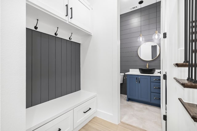 mudroom with wooden walls, sink, and light hardwood / wood-style flooring