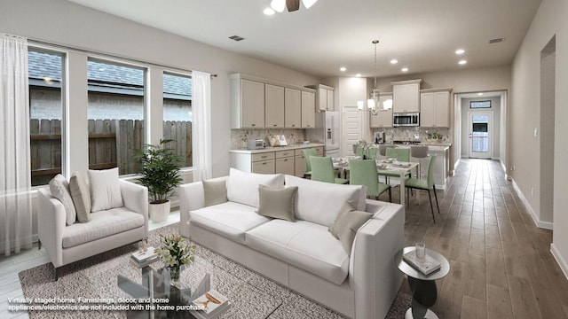 living area with baseboards, visible vents, wood finished floors, a chandelier, and recessed lighting