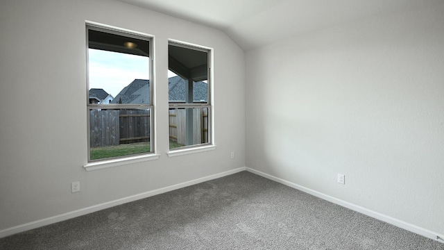 carpeted spare room featuring lofted ceiling and baseboards