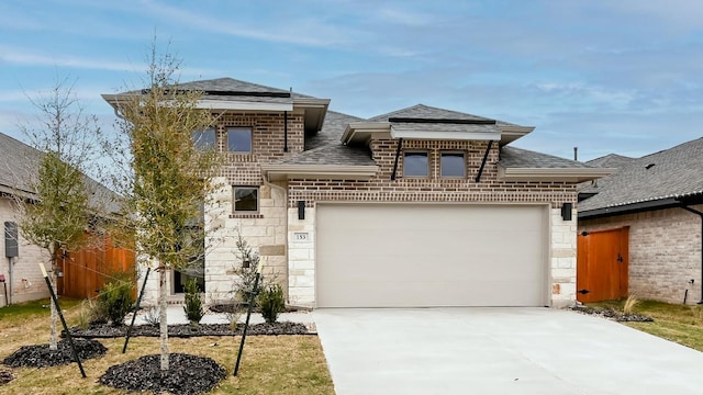 view of front of property with an attached garage, stone siding, driveway, and roof with shingles