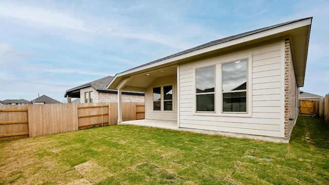 back of house featuring a patio, a lawn, and a fenced backyard