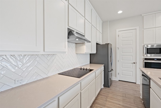 kitchen with light hardwood / wood-style floors, range hood, white cabinets, decorative backsplash, and stainless steel appliances