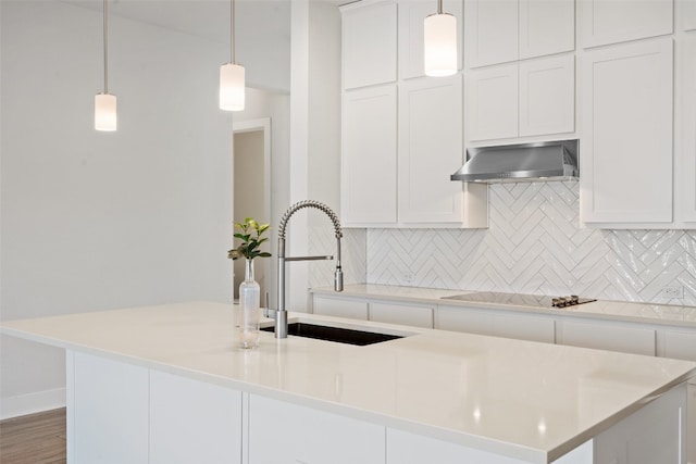 kitchen featuring hanging light fixtures, black electric stovetop, a kitchen island with sink, and extractor fan