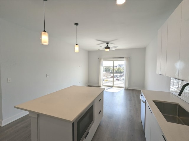 kitchen featuring sink, dark wood-type flooring, white cabinetry, a center island, and stainless steel microwave