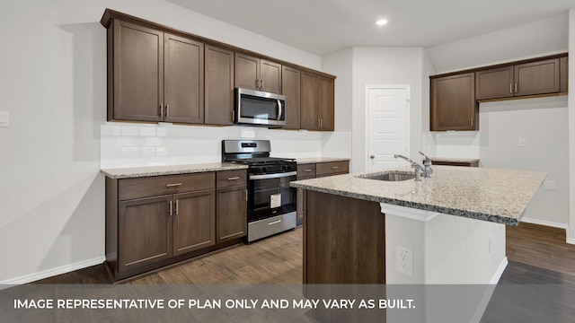 kitchen featuring dark wood-type flooring, a kitchen island with sink, sink, appliances with stainless steel finishes, and dark brown cabinetry