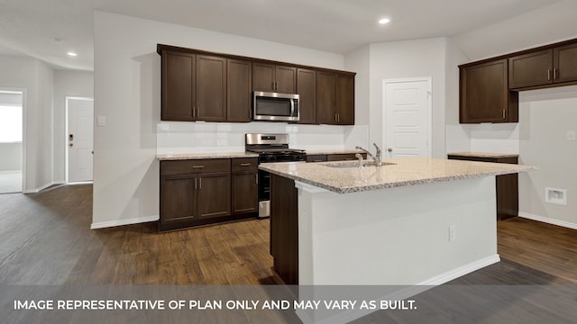 kitchen featuring appliances with stainless steel finishes, light stone counters, dark hardwood / wood-style flooring, a center island with sink, and sink