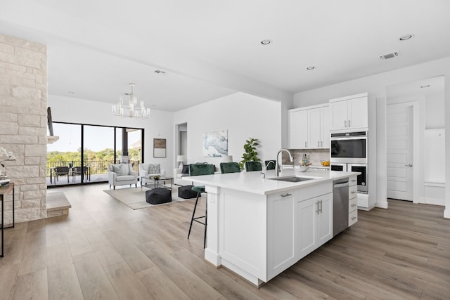 kitchen featuring sink, white cabinets, a center island with sink, and appliances with stainless steel finishes