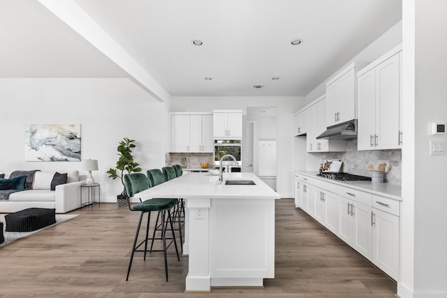 kitchen featuring an island with sink, appliances with stainless steel finishes, tasteful backsplash, a kitchen bar, and white cabinetry