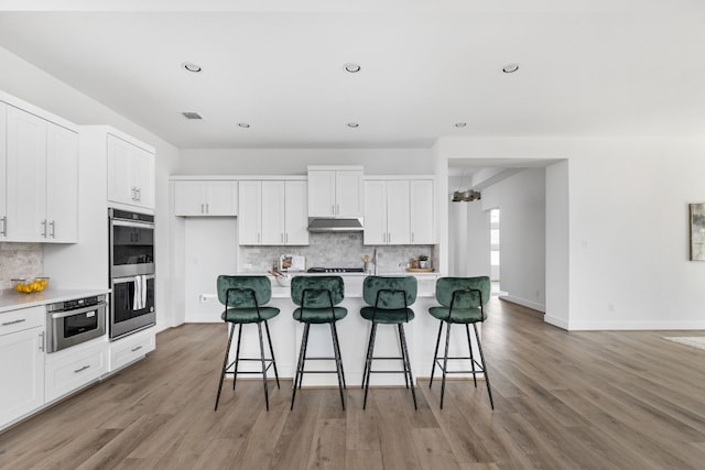 kitchen with a center island with sink, white cabinetry, and a breakfast bar area