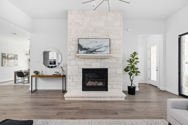 living room with wood-type flooring and a stone fireplace