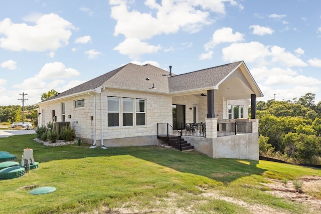 back of property featuring a lawn and ceiling fan