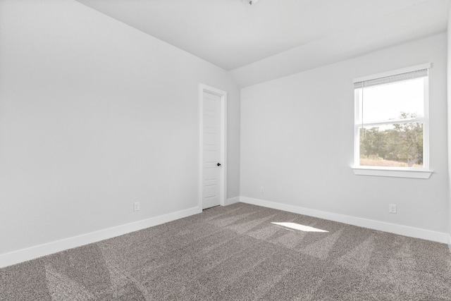 carpeted spare room with baseboards and vaulted ceiling