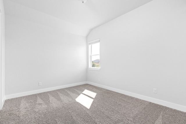 carpeted spare room with vaulted ceiling