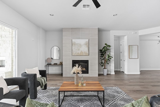 living room with a large fireplace, dark hardwood / wood-style floors, and ceiling fan